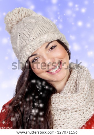 Attractive girl with with wool hat and scarf isolated on blue background with snow