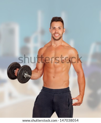 Muscled guy lifting weights in the gym