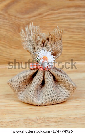 Brown bag closed with a ribbon and a flower on a wooden background
