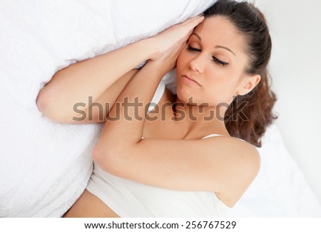 Brunette young woman sleeping in her bed