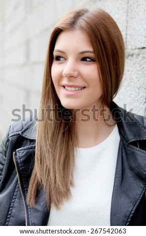 Cool young woman with black leather jacket and a grey wall of background