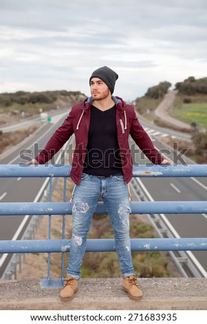 Cool handsome man at the top of a bridge over a highway