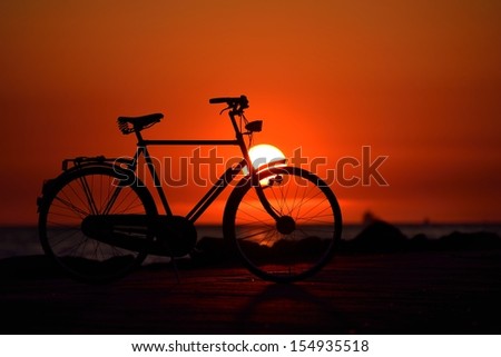 Old dutch retro bicycle on the beach against red sunset