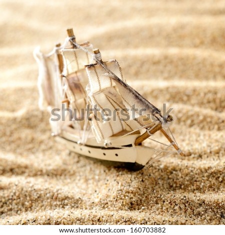 wooden sail ship toy model in the sea sand close-up