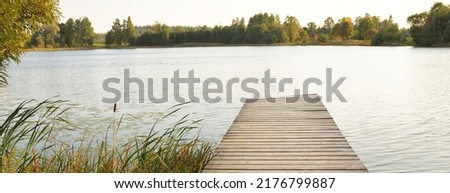Lake shore at sunset. Wooden pier close-up. Reflections in the water. Idyllic rural scene. Pastoral landscape. Ecological resort, fishing, swimming. Early autumn Foto d'archivio © 