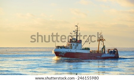 Frozen fishing vessel in coming back to the port at the sunset