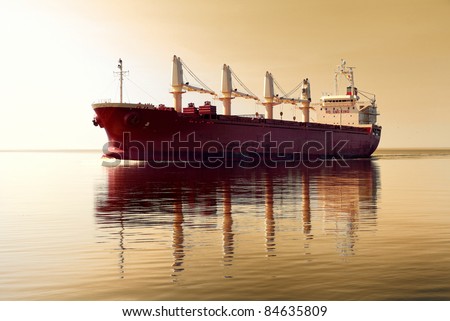 cargo ship sailing in still water against sunset sky