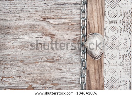 Lace fabric with chain and seashell on the old wood