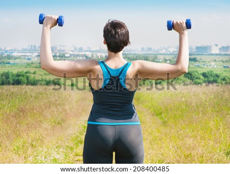 Plus size woman exercising with dumbbells