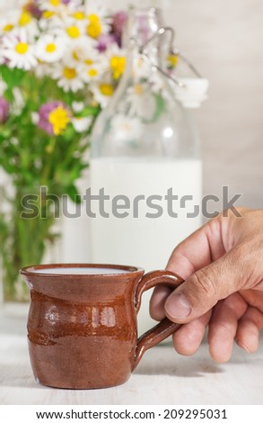 Man hand holding ceramic mug with milk