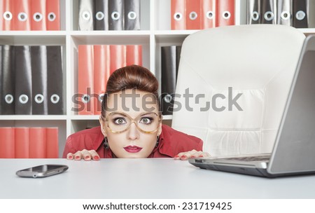 Business woman hiding behind table and afraid