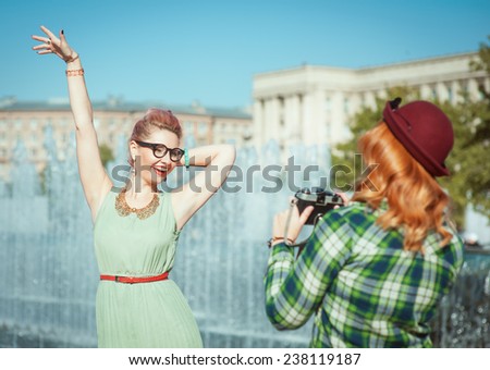 Two beautiful hipster girls taking pictures on an old camera