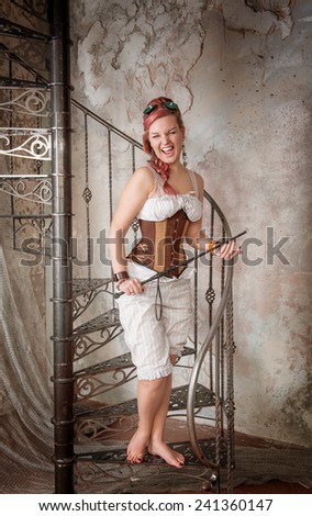 Beautiful screaming steampunk woman in trousers with whip on the stairway