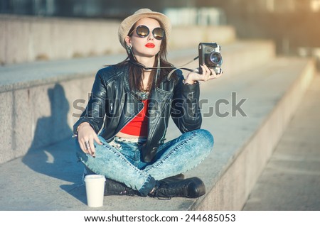 Young fashion beautiful girl in leather jacket with retro camera in the city