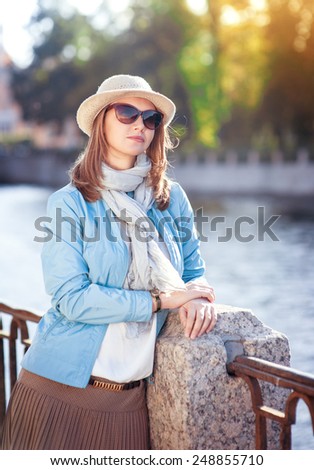 Beautiful young woman in hat, sunglasses and scarf outdoor in the city