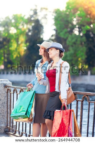Two beautiful girls with shopping bags and cup of coffee in the city outdoor