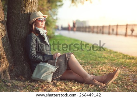 Beautiful young woman in hat and scarf enjoy sunlight outdoor in the city