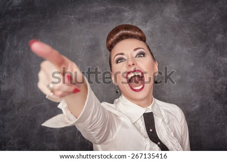 Angry screaming woman in white blouse pointing out on the chalkboard background