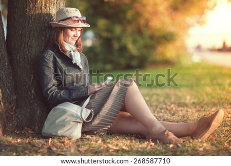 Beautiful young woman in hat and scarf with mobile phone outdoor