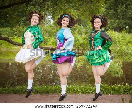 Three young beautiful girls in irish dance dress and wig dancing outdoor