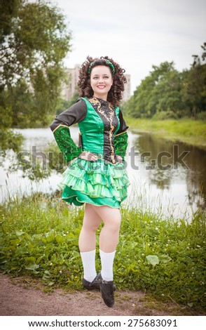 Young beautiful girl in irish dance dress and wig posing outdoor