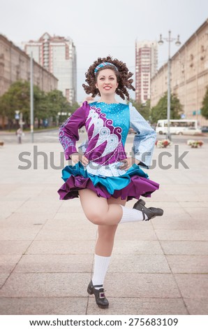 Young woman in irish dance dress and wig dancing outdoor