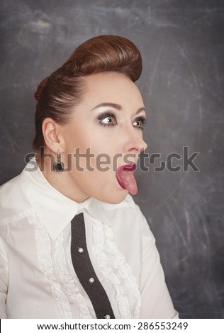 Business woman showing long tongue on the blackboard background