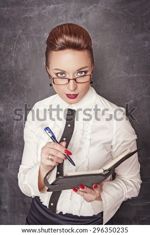 Business woman with notebook and pen on the blackboard background