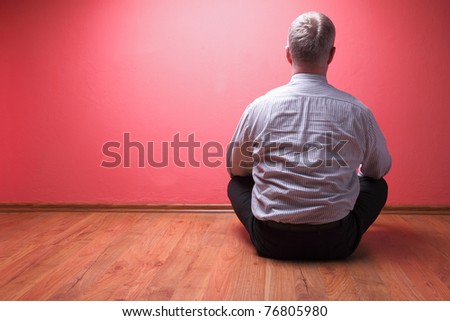 men sited in the floor on red wall background