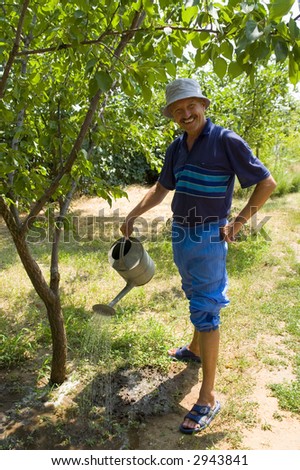 Smiling Man Watering His Orchard