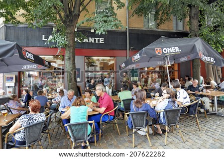 BRUSSELS, BELGIUM - JULY 27, 2014: People drink, eat and talk on the terrace of a cafe in the Old Market area of Brussels on July 27, 2014 in Brussels. a group of musicians play music