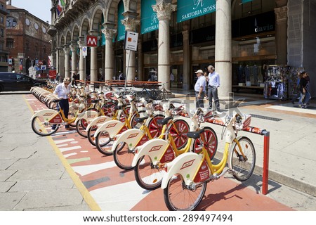MILAN, ITALY- JUNE 11, 2015: Women take a bike for rent  in the bike station sharing at The Duomo Piazza in Milan. Symbol of mobility, ecology and alternative energy