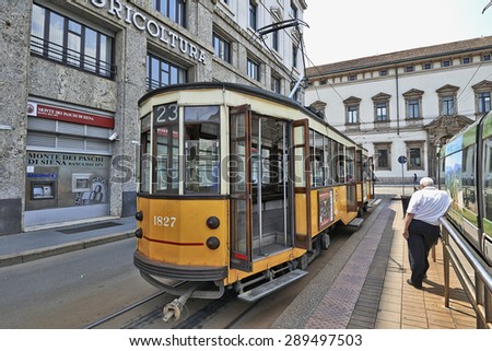 MILAN, ITALY- JUNE 11, 2015: Milan Orange Cable Car and a man from back waiting for departure on tramway platform in Milan, Italy . Symbol of mobility, ecology and alternative energy