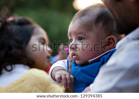 portrait of father and son against nature background, Indian man holding his son in lap.