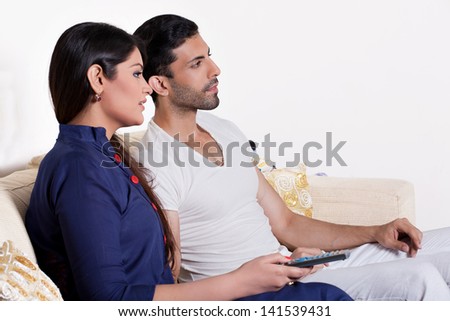 young couple relaxing on the sofa in tv lounge, Indian couple watching movie