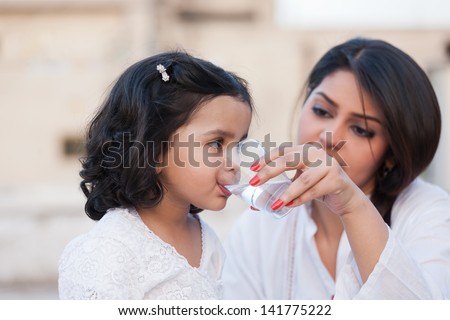 mother giving water to little daughter, indian mother and daughter