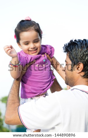 father tossing up the daughter in air, happy indian man tossing his daughter in the air