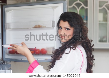 Indian woman opening the door of refrigerator