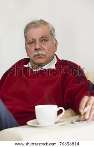 retired old man relaxing and having a cup of tea in an old age home.