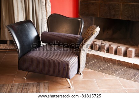 single sofa seat in front of a fireplace and a curtain