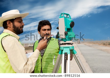 two civil engineers doing a survey on a construction site. Engineers doing land survey at a construction site