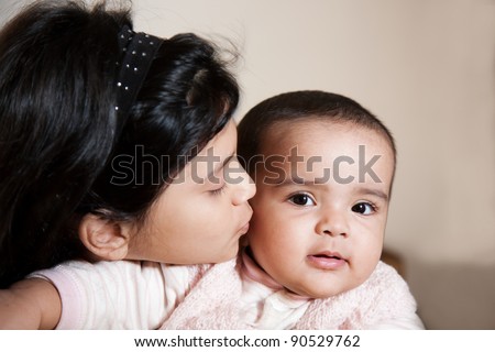little muslim girl kissing her sister while holding her in the lap