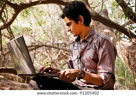 remote connectivity, man sitting under the trees in jungle and working on the laptop, Indian man.
