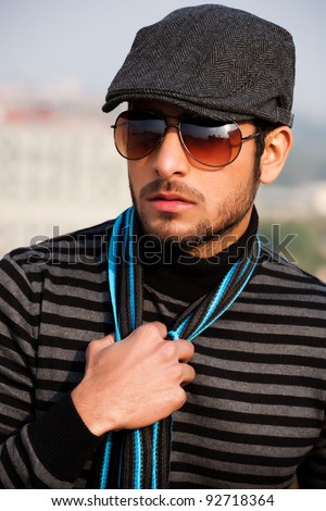 portrait of a handsome and confident man wearing sweater and cap in outdoor, handsome man wearing sunglasses