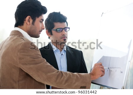 two young businessmen discussing business strategy in a meeting, Indian business man with latin american colleague, two serious businessmen,