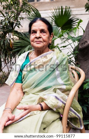 portrait of a graceful senior indian woman, senior Indian woman sitting in the lawn or garden