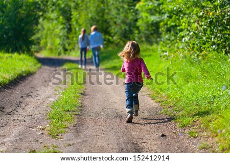 A little girl running down the road for her mother and sister