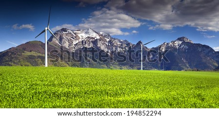 Electric wind turbines in the field of winter wheat in the Alps, near the village of Les Moras, Pellafol, France.