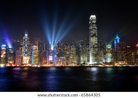 Stunning sight seeing of the Victoria harbor in Hong Kong illuminated at nighttime with futuristic buildings and colorful lights.