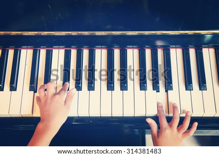 Children\'s fingers on the keys of a piano playing